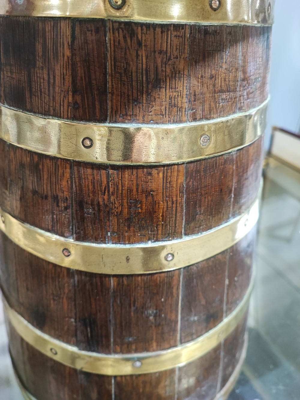 An antique coopered oak stick stand bound with polished riveted brass bands and topped with a flared brass collar. View V