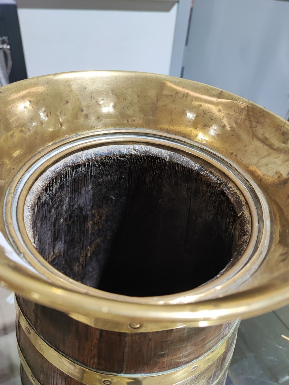 An antique coopered oak stick stand bound with polished riveted brass bands and topped with a flared brass collar. View VI