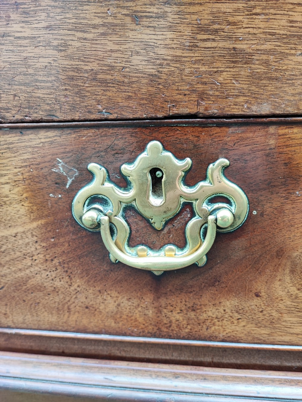 A George III mahogany storage trunk featuring a hinged top lid, two lower drawers, and brass batwing escutcheon handles. View II
