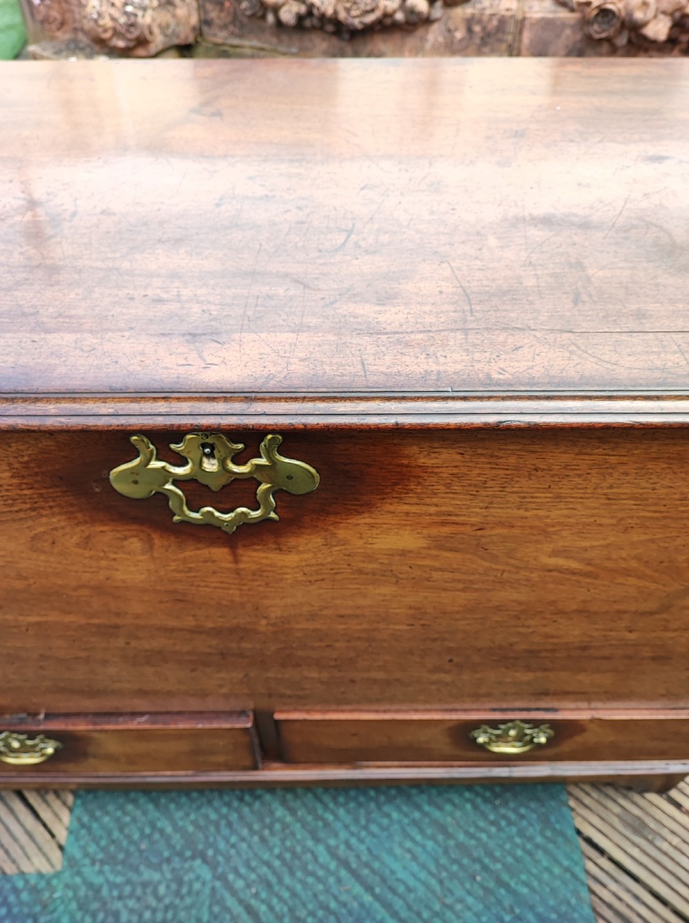 A George III mahogany storage trunk featuring a hinged top lid, two lower drawers, and brass batwing escutcheon handles. View III