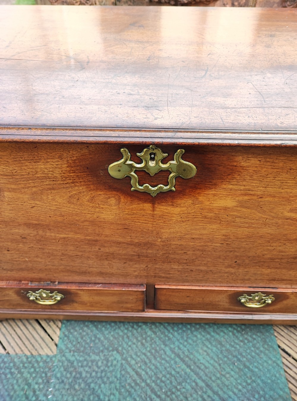 A George III mahogany storage trunk featuring a hinged top lid, two lower drawers, and brass batwing escutcheon handles. View XII