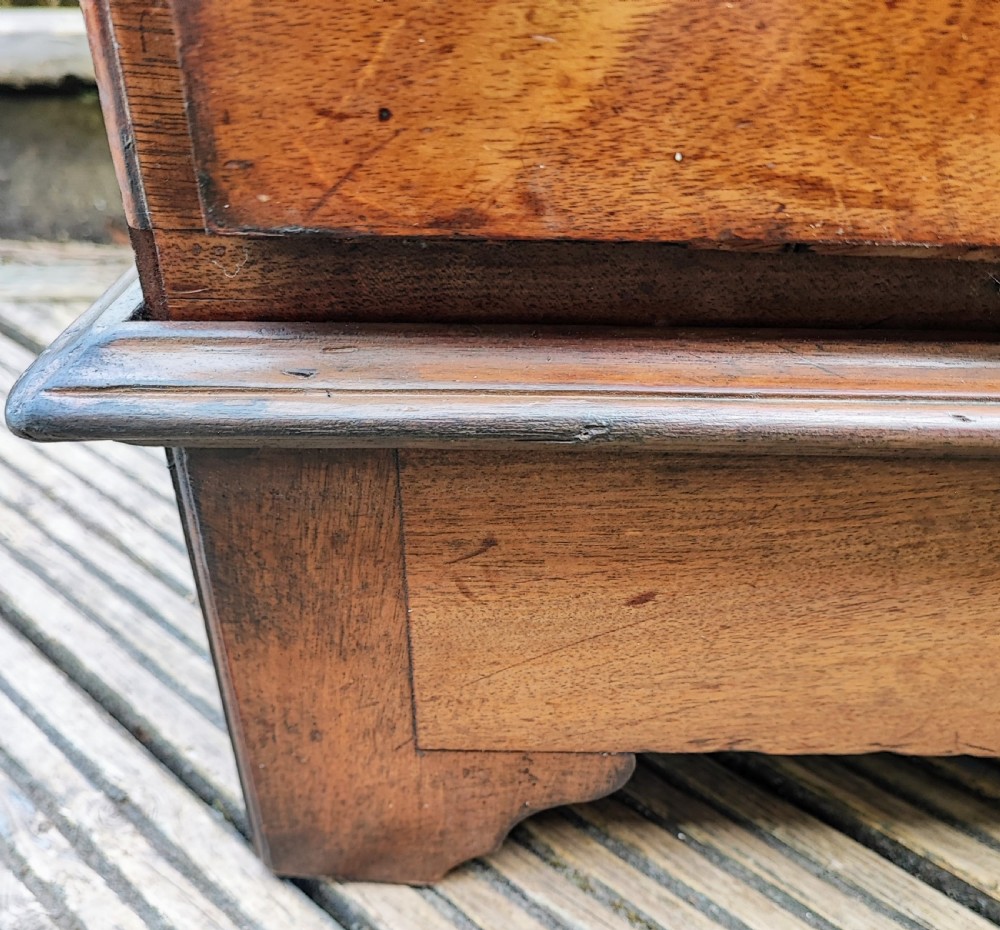 A George III mahogany storage trunk featuring a hinged top lid, two lower drawers, and brass batwing escutcheon handles. View XIII