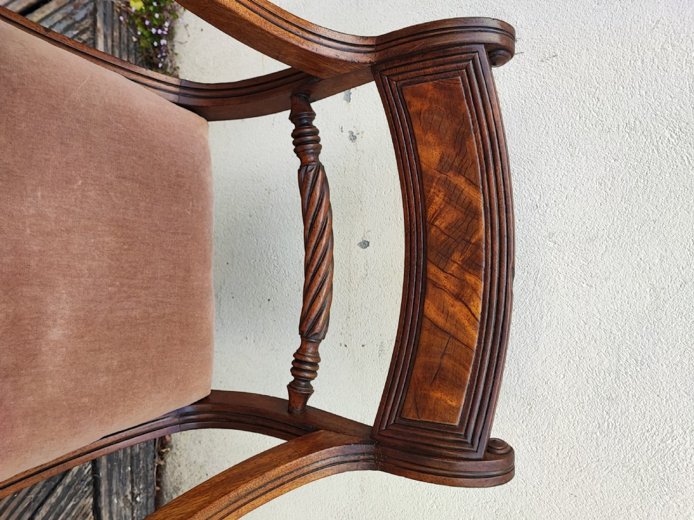 A side view of a Regency period mahogany armchair featuring carved scroll arms, sabre legs, and a padded seat. View IV