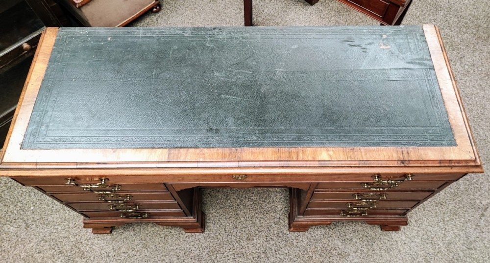 An eighteenth-century Georgian mahogany kneehole desk featuring a leather writing surface, multiple drawers with brass handles, a central recessed cupboard, and bracket feet. View V
