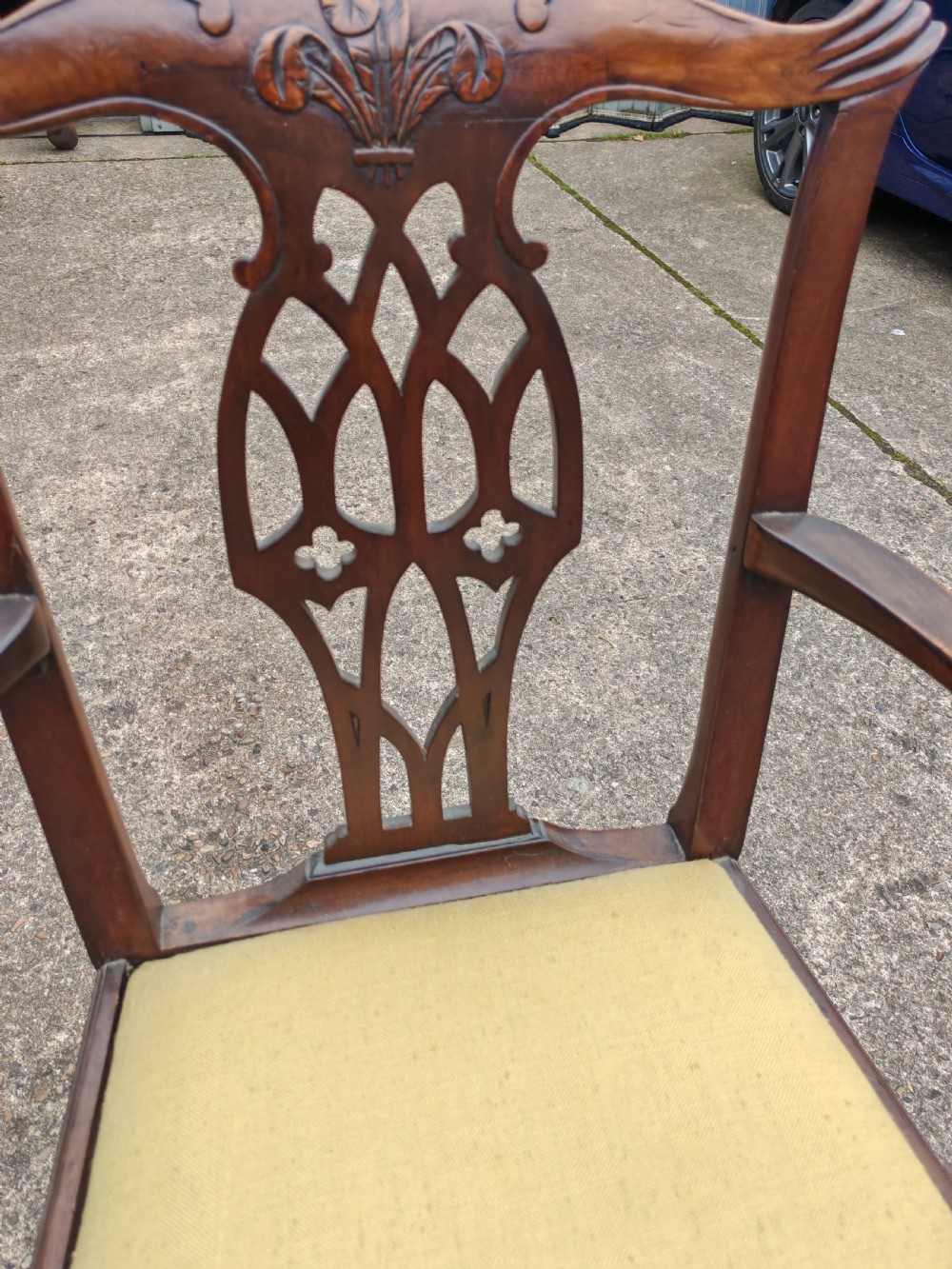 A Georgian mahogany carver armchair featuring a carved pierced back splat, swept arms, and a light yellow drop-in seat cushion. View IV