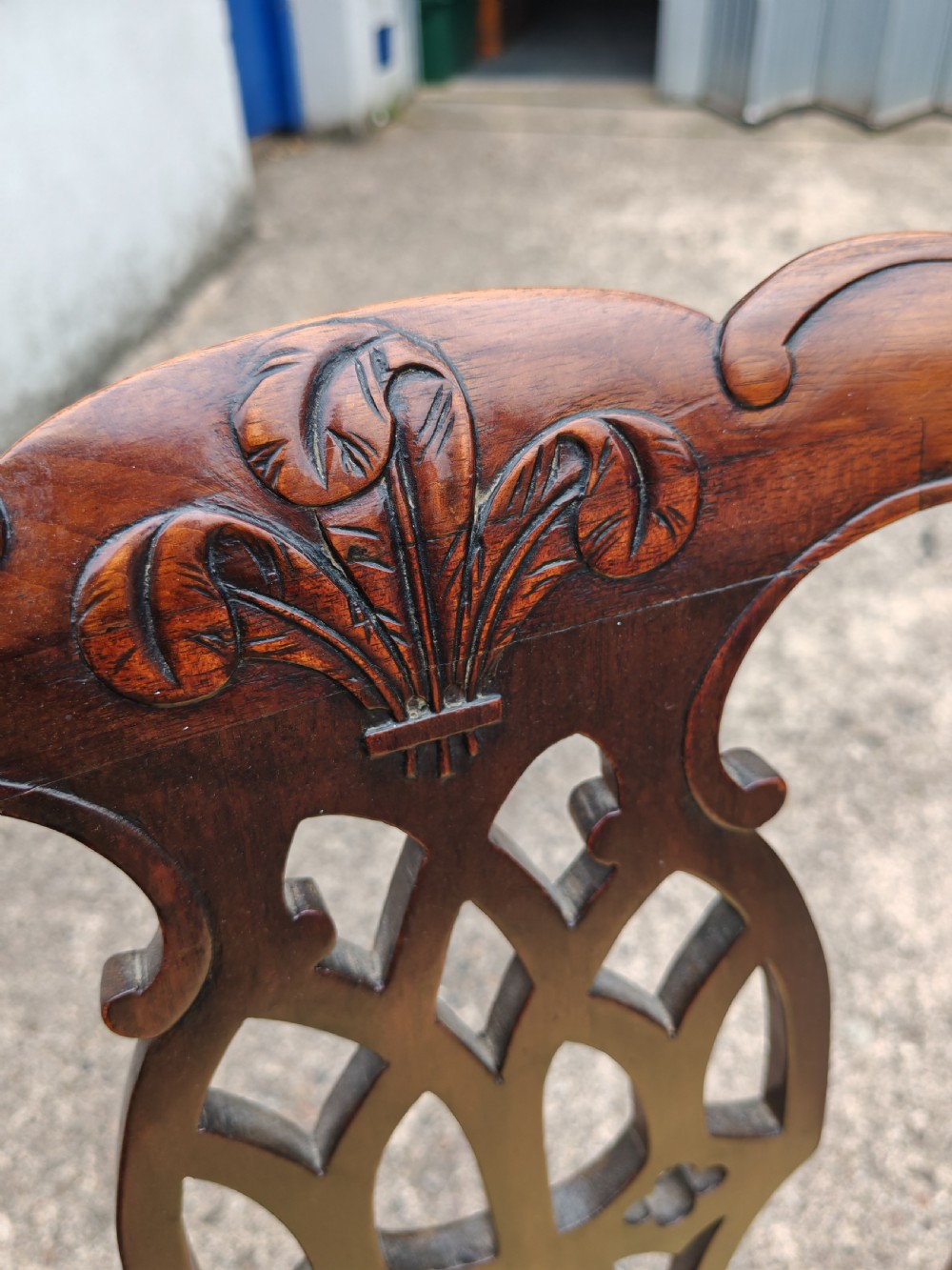 A Georgian mahogany carver armchair featuring a carved pierced back splat, swept arms, and a light yellow drop-in seat cushion. View V