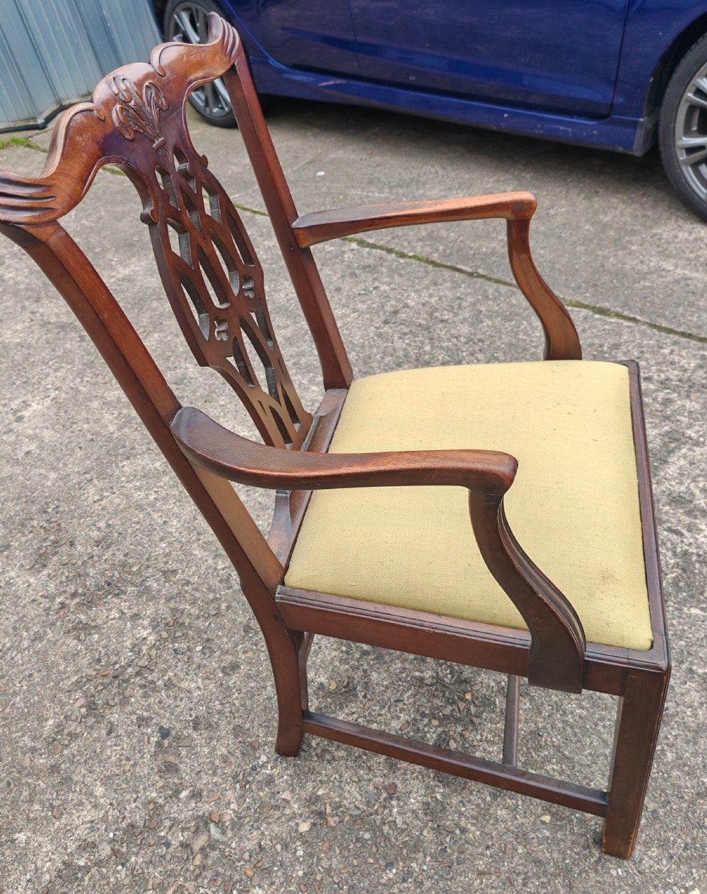 A Georgian mahogany carver armchair featuring a carved pierced back splat, swept arms, and a light yellow drop-in seat cushion. View VII