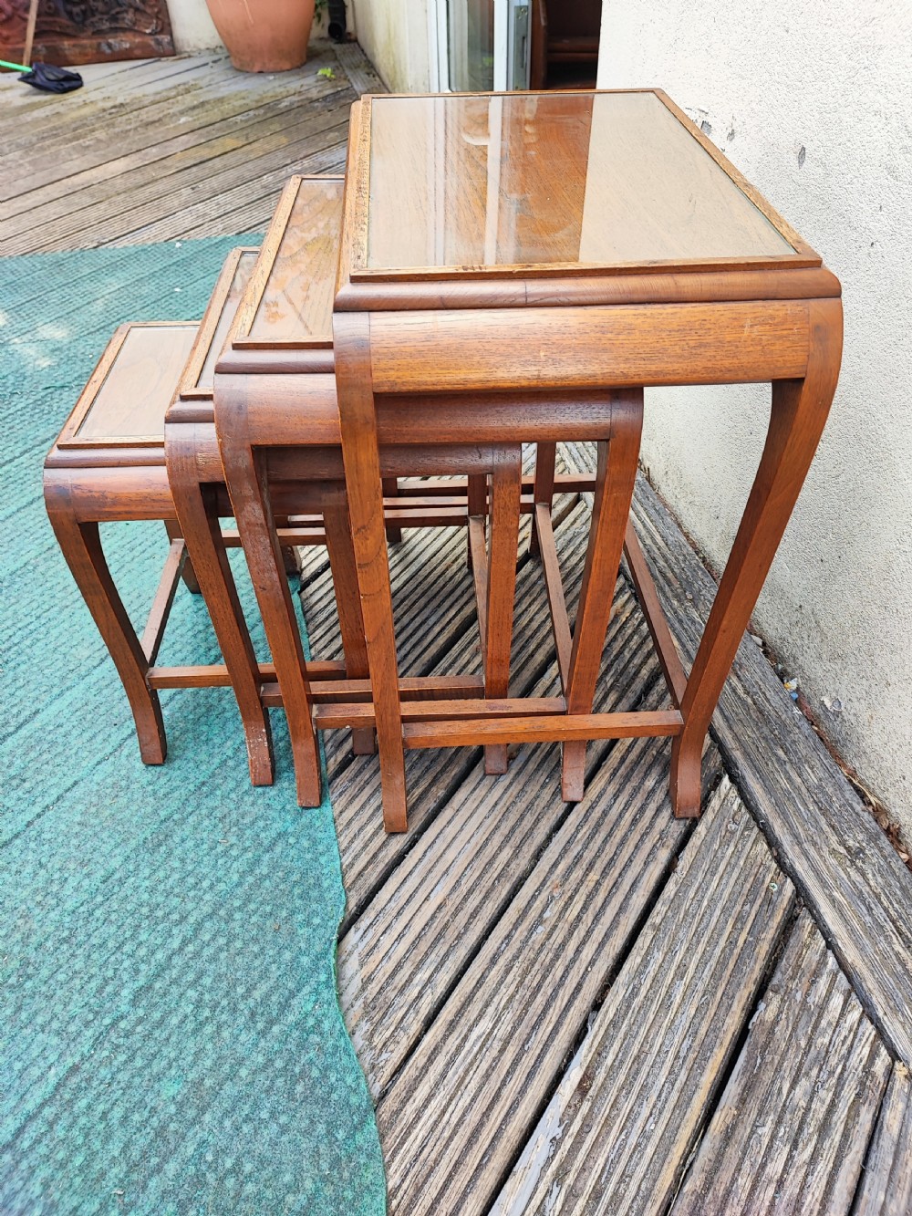 A set of four graduated dark hardwood nesting tables featuring hand-carved floral borders along the aprons and curved legs. View II