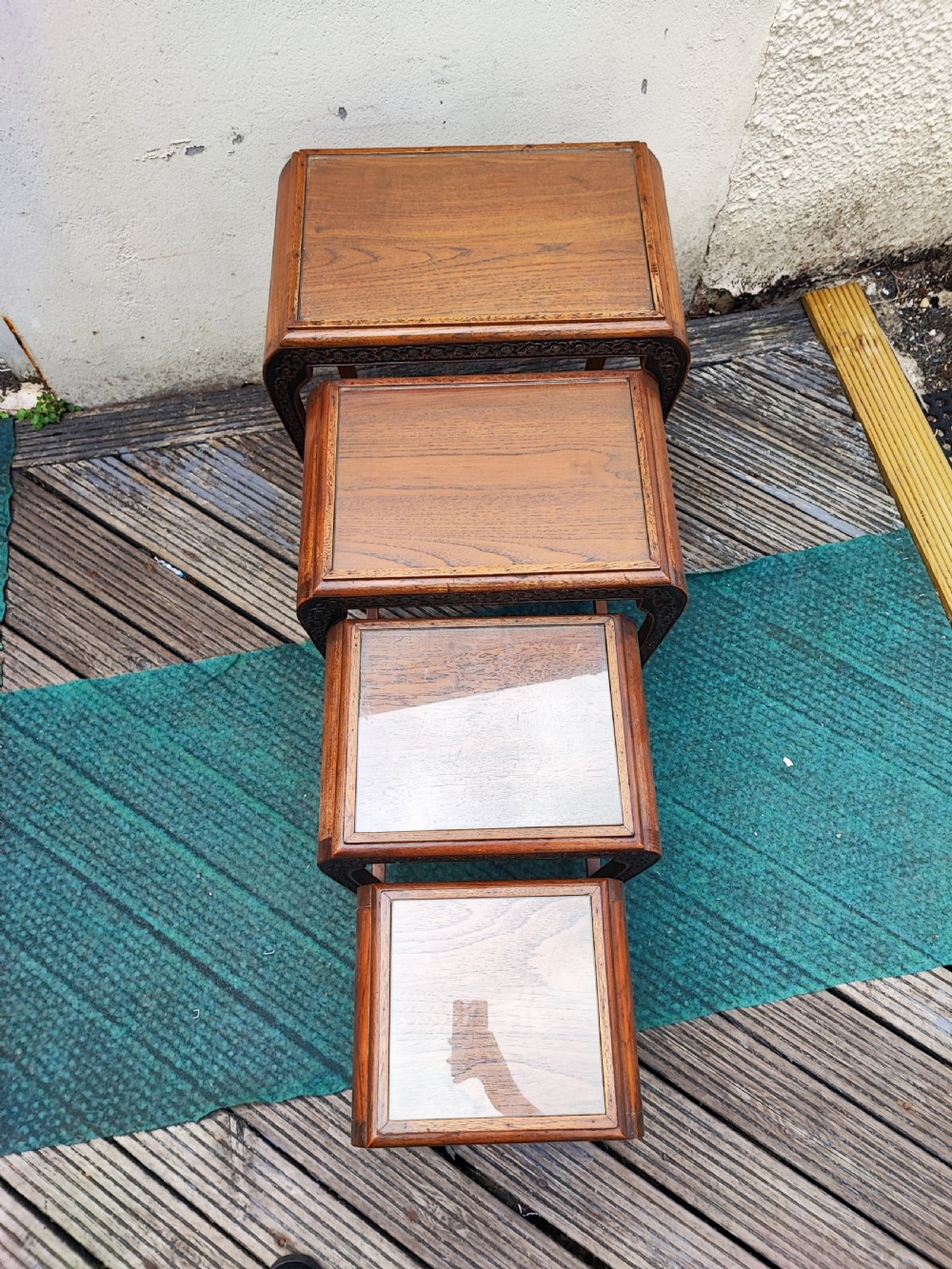 A set of four graduated dark hardwood nesting tables featuring hand-carved floral borders along the aprons and curved legs. View VI