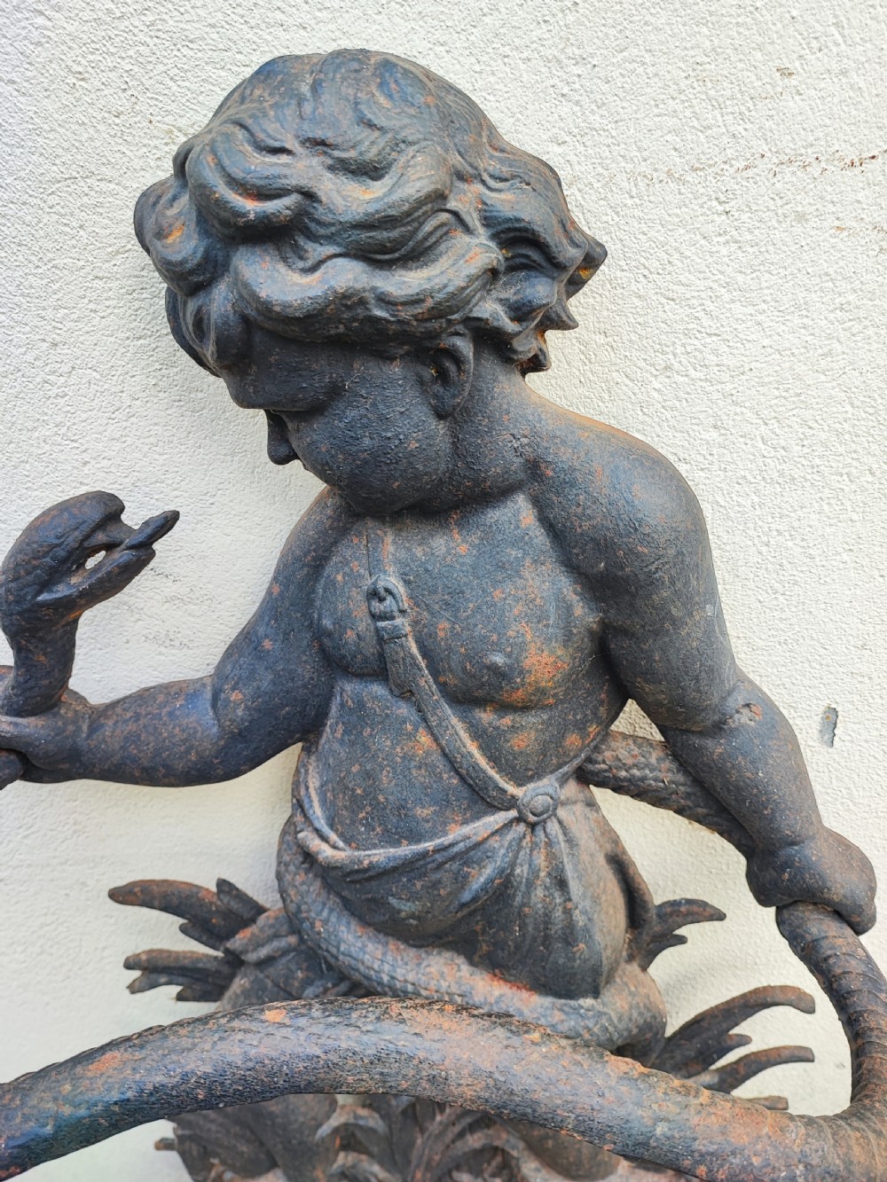 A Victorian cast iron stick stand featuring a figure of a young boy holding a serpent on a leafy base with an integrated drip tray. View II