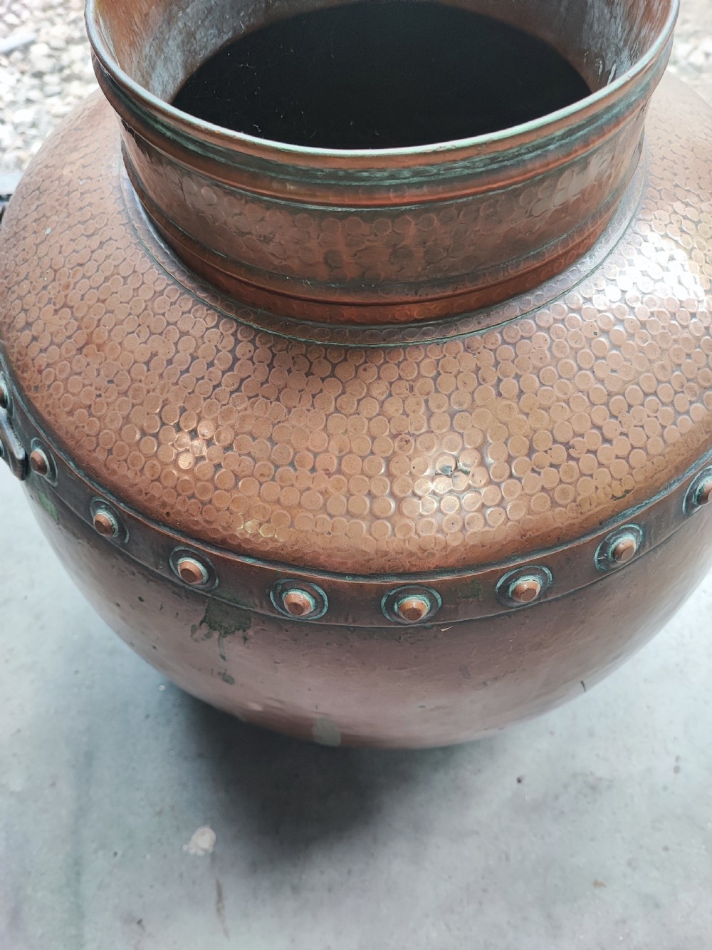 A large, rounded Arts and Crafts copper vessel featuring a hand-hammered shoulder, riveted metal band, and dual side handles. View II