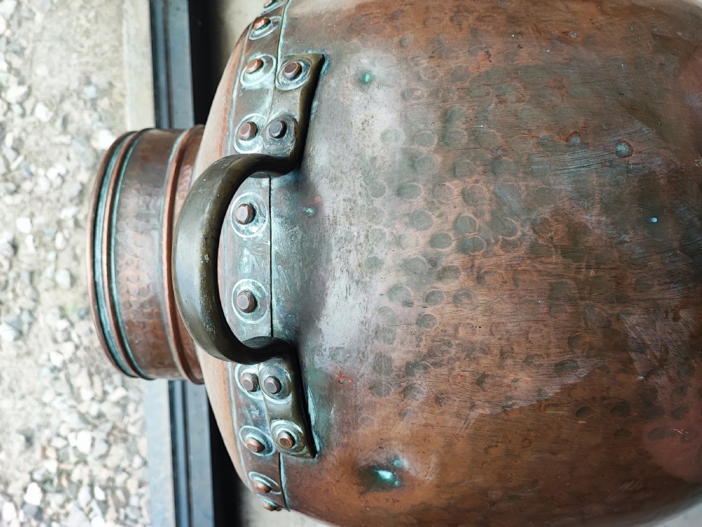A large, rounded Arts and Crafts copper vessel featuring a hand-hammered shoulder, riveted metal band, and dual side handles. View III