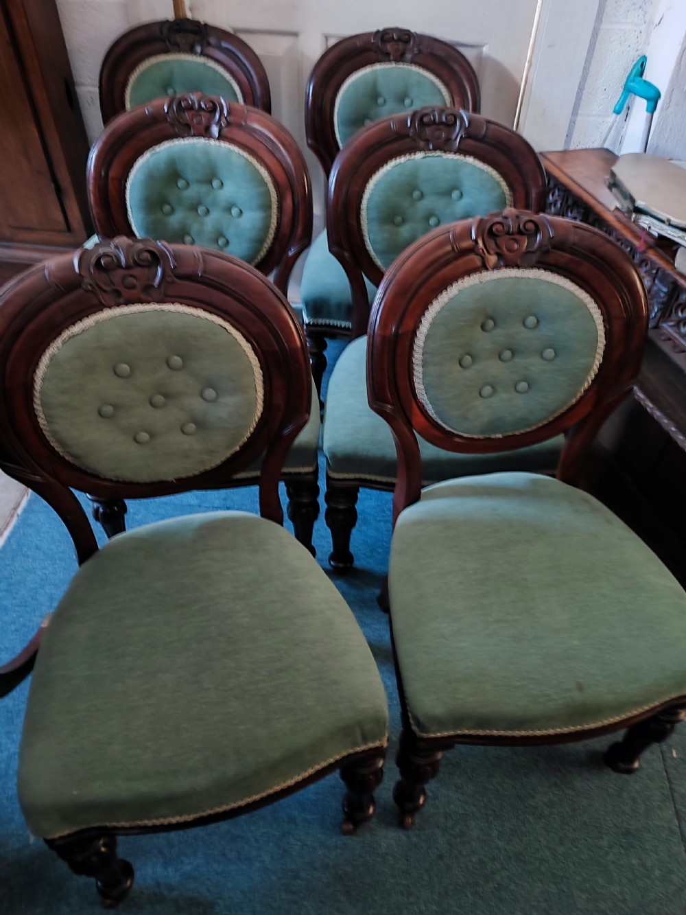 A set of six Victorian mahogany dining chairs featuring carved balloon backs, green buttoned upholstery, and turned front legs. View IV