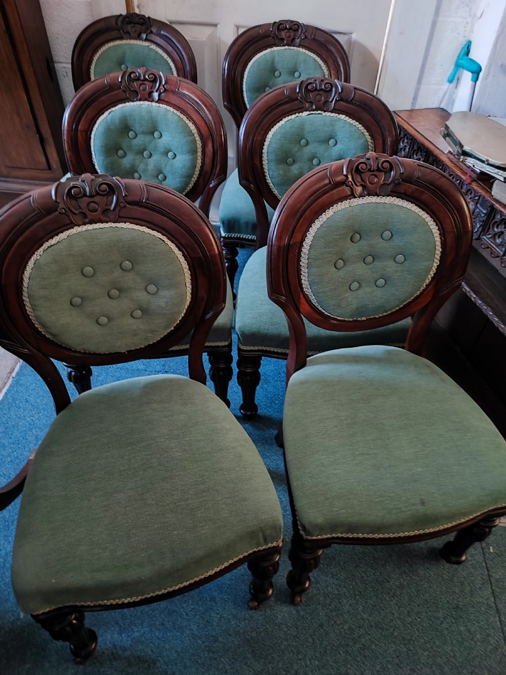 A set of six Victorian mahogany dining chairs featuring carved balloon backs, green buttoned upholstery, and turned front legs. View V