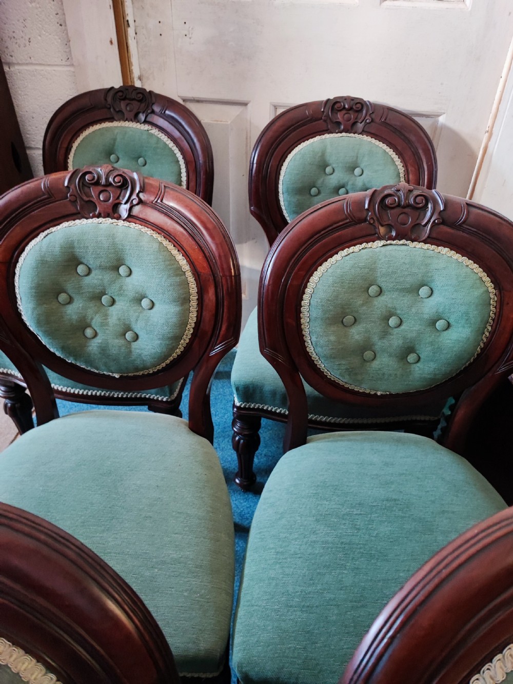 A set of six Victorian mahogany dining chairs featuring carved balloon backs, green buttoned upholstery, and turned front legs. View VI