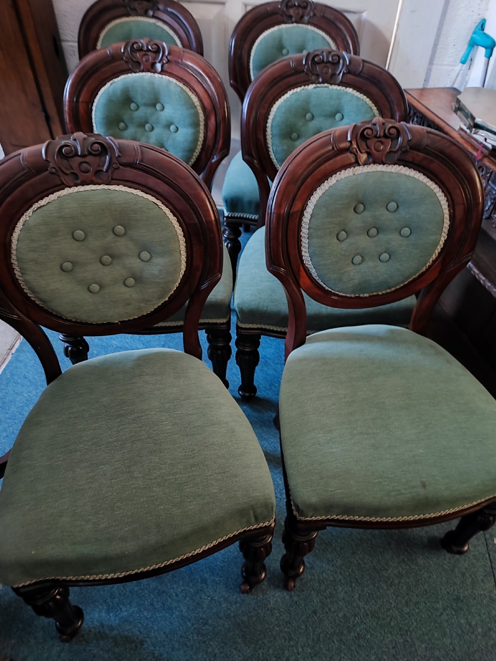 A set of six Victorian mahogany dining chairs featuring carved balloon backs, green buttoned upholstery, and turned front legs. View VII