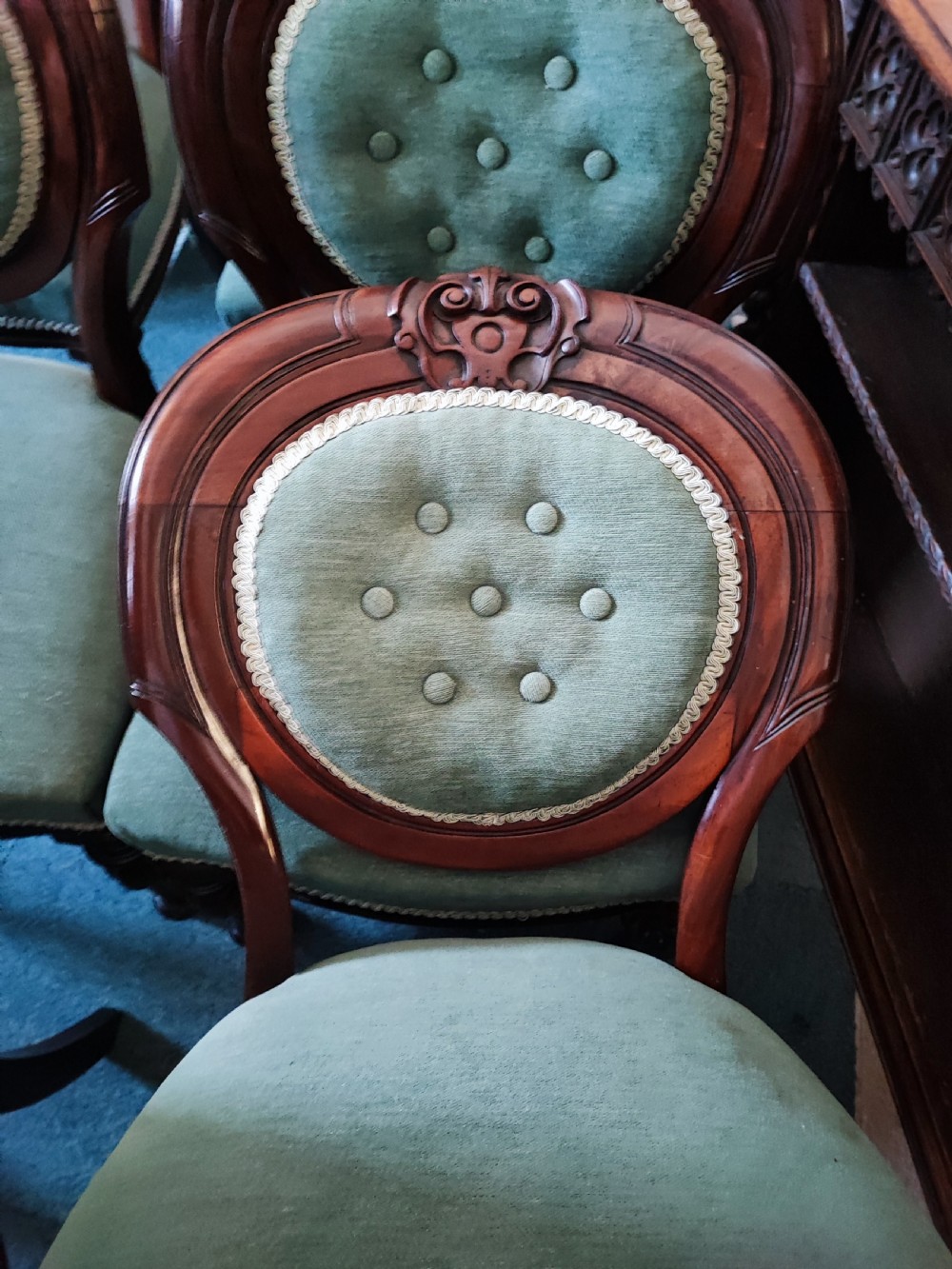 A set of six Victorian mahogany dining chairs featuring carved balloon backs, green buttoned upholstery, and turned front legs. View VIII