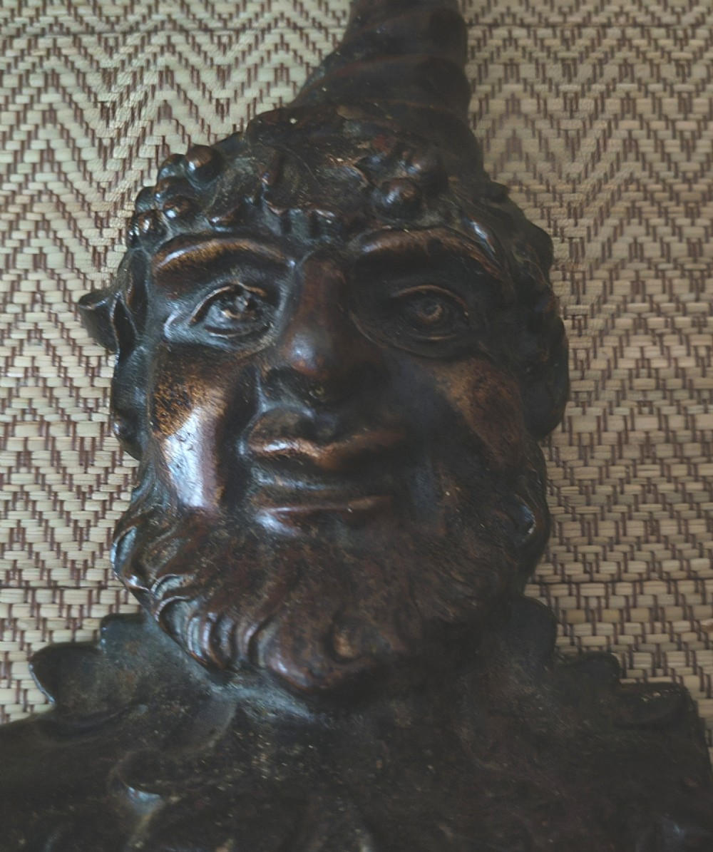 A dark brown cast iron doorstop featuring a sculpted bust of a bearded folklore figure wearing a curved pointed hat. View II