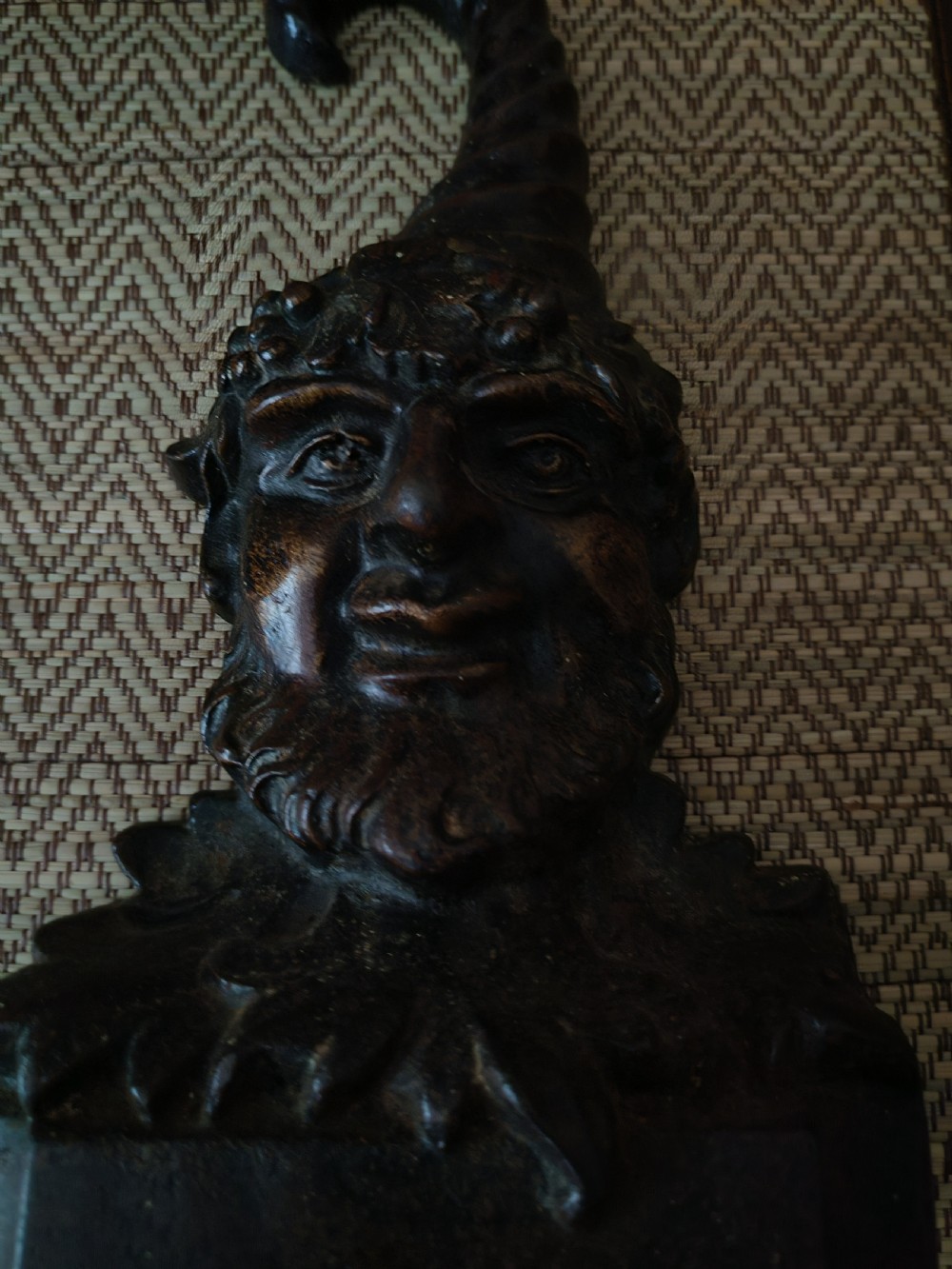 A dark brown cast iron doorstop featuring a sculpted bust of a bearded folklore figure wearing a curved pointed hat. View IX