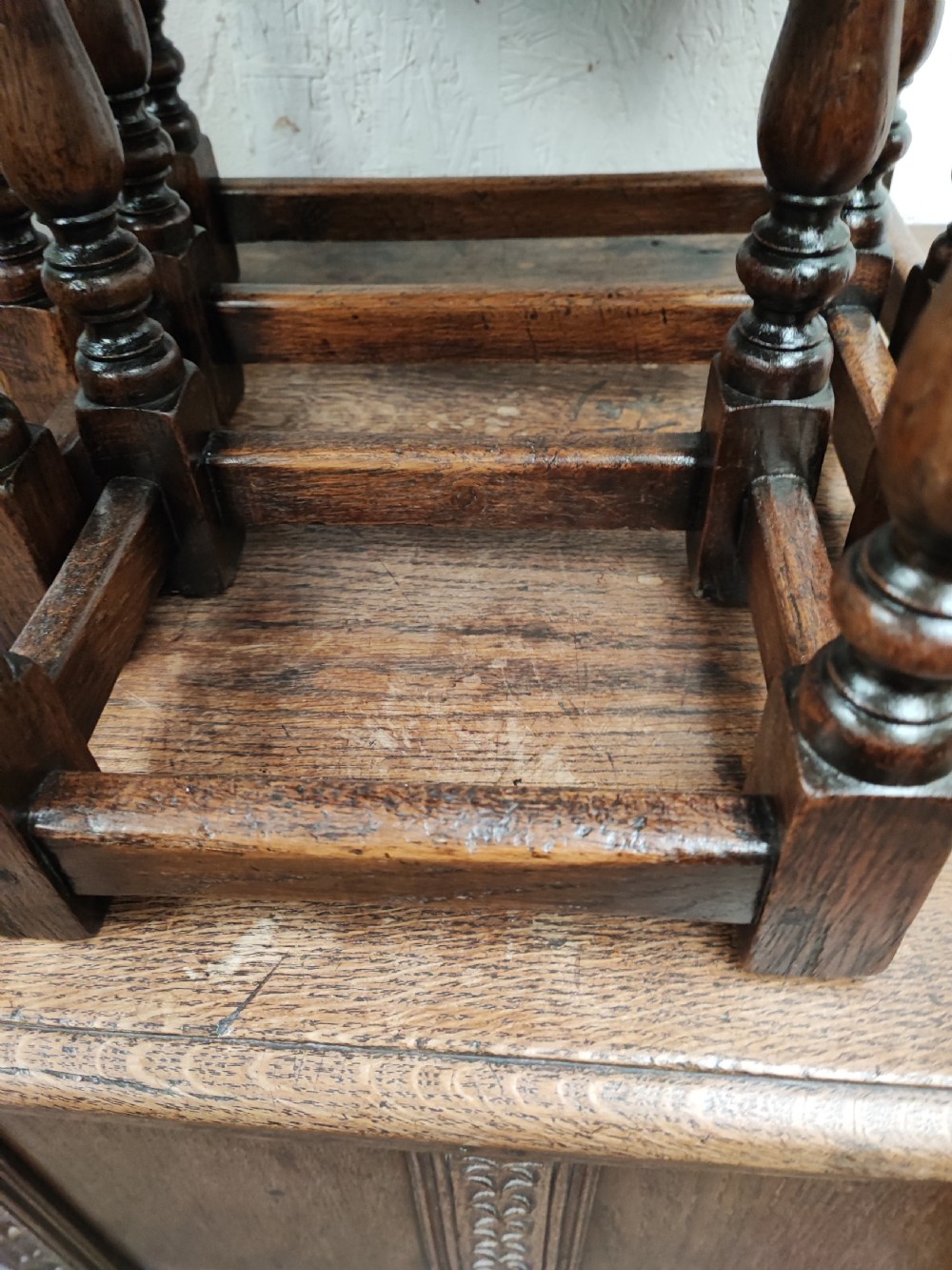 A set of three graduated dark oak nesting tables featuring turned legs and moulded top edges stacked together. View VI