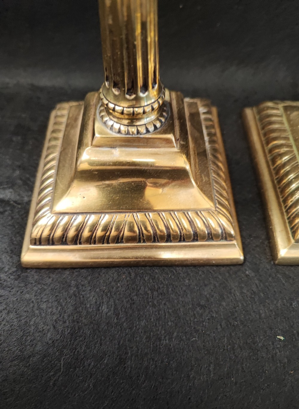 A pair of Georgian brass candlesticks featuring fluted columns, square stepped bases with gadrooned trim, and removable square nozzles. View II