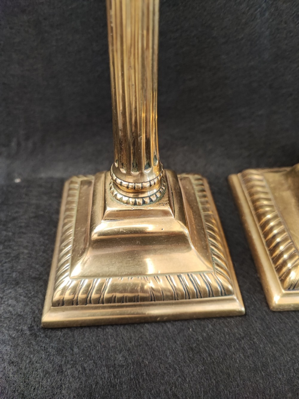 A pair of Georgian brass candlesticks featuring fluted columns, square stepped bases with gadrooned trim, and removable square nozzles. View VII