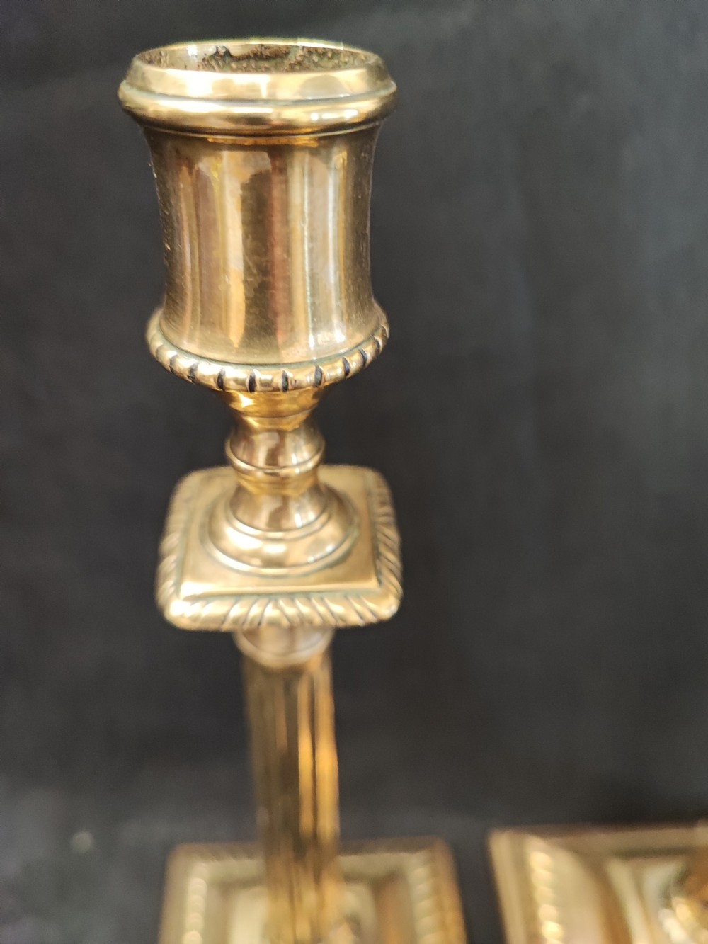 A pair of Georgian brass candlesticks featuring fluted columns, square stepped bases with gadrooned trim, and removable square nozzles. View VIII
