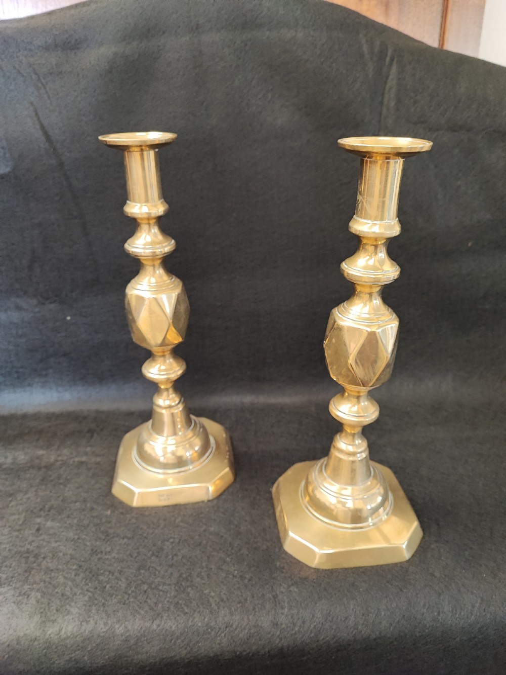 A pair of polished Victorian brass candlesticks featuring diamond-faceted central knops and octagonal stepped bases stamped with maker details. View II