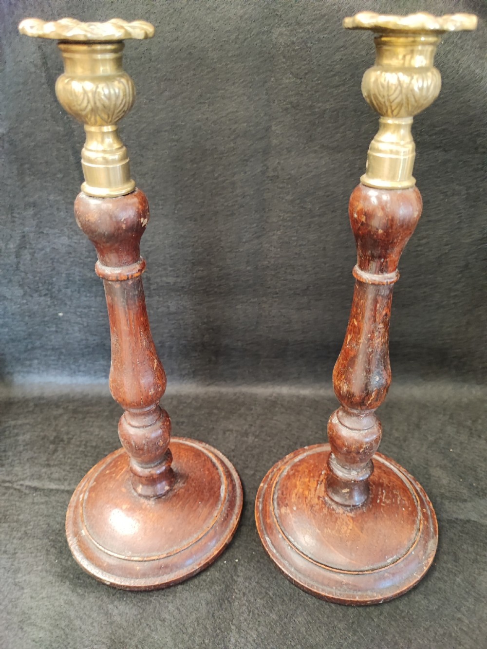 A pair of antique candle sticks in oak and brass. View II