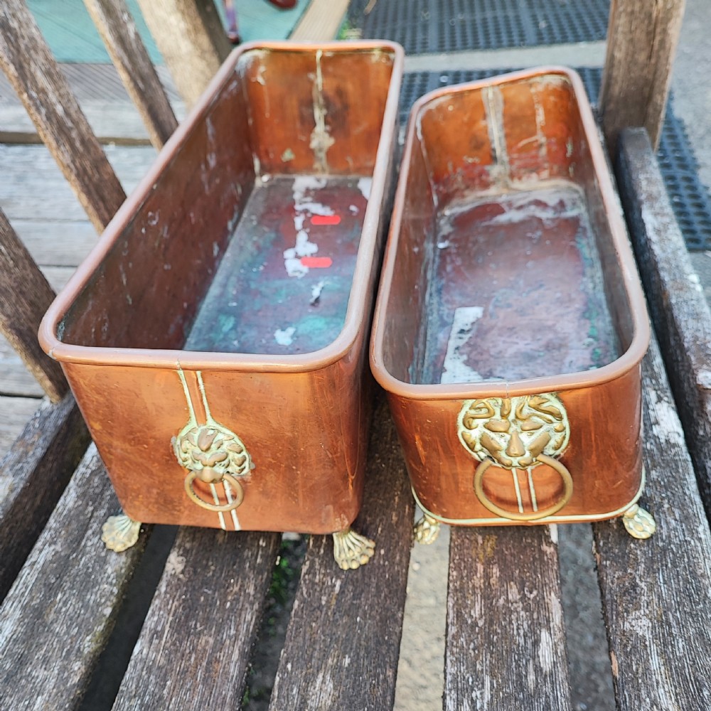 A pair of rectangular copper plant troughs featuring lion mask brass ring handles and claw feet.