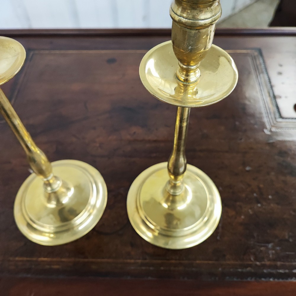 A matching pair of 19th-century cast brass candlesticks featuring turned baluster stems, circular drip pans, and stepped round bases. View III