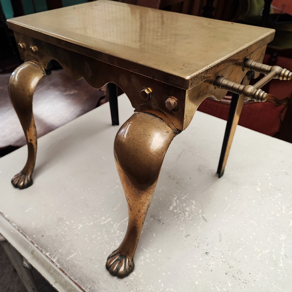 A Georgian brass hearth footman featuring a smooth rectangular top, side drop handles, a scalloped apron, and front cabriole legs with paw feet. View III