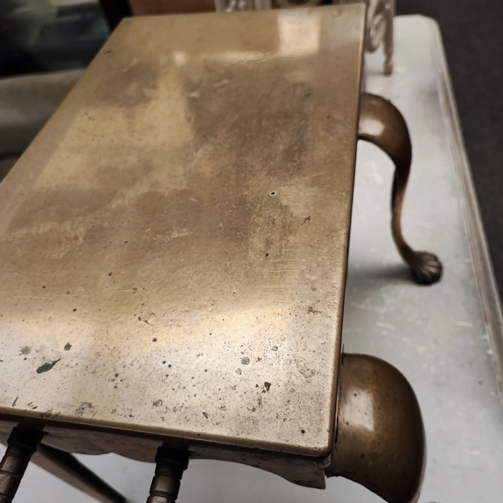 A Georgian brass hearth footman featuring a smooth rectangular top, side drop handles, a scalloped apron, and front cabriole legs with paw feet. View IV