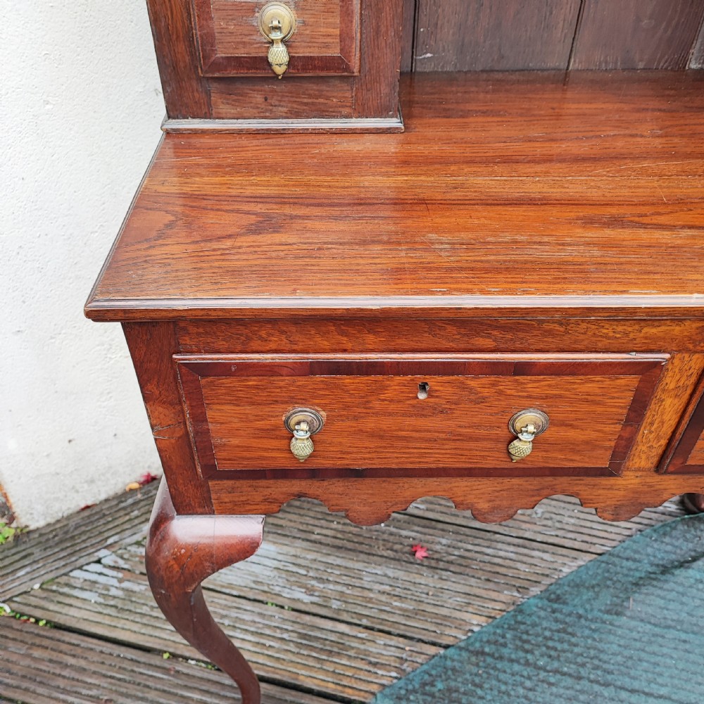 An antique dark oak small dresser featuring an open shelving unit with side cupboards over a two-drawer base raised on cabriole legs. View VII