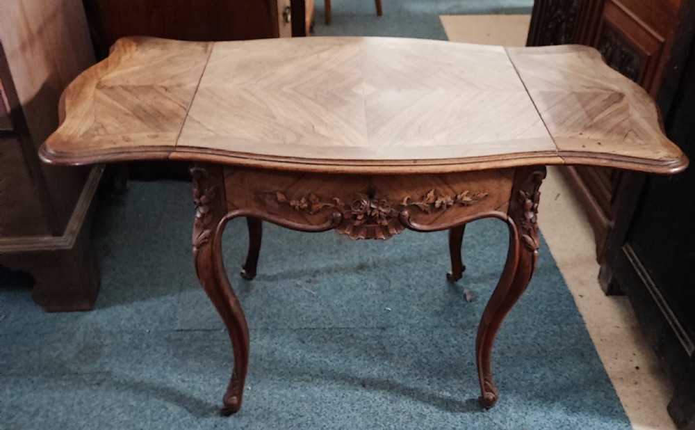 An antique French rosewood side table featuring a parquetry top with extendable side leaves, carved floral apron details, and slender cabriole legs. View III