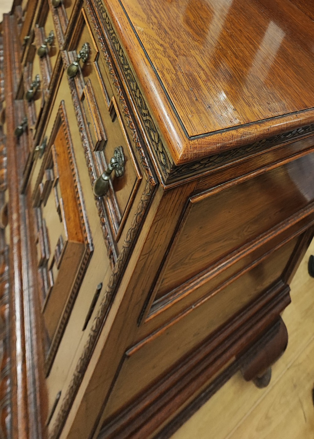 A carved dark oak sideboard featuring geometric panelled cupboard doors, multiple drawers with brass drop handles, cabriole legs, and a low upstand. View II