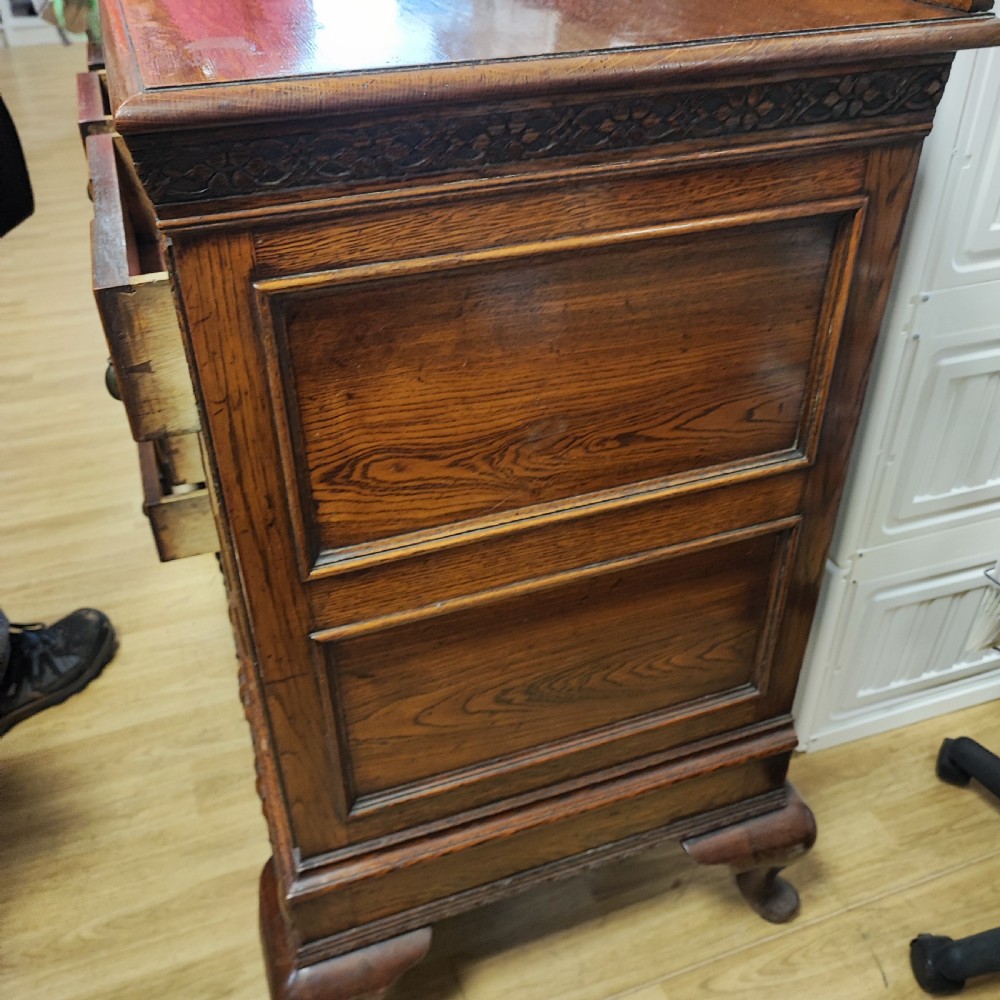 A carved dark oak sideboard featuring geometric panelled cupboard doors, multiple drawers with brass drop handles, cabriole legs, and a low upstand. View VIII