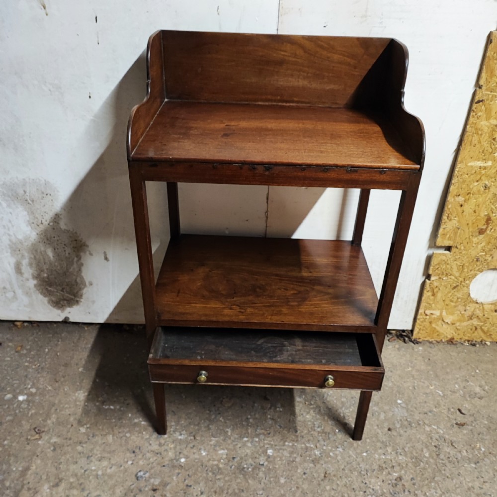 A Georgian mahogany bedside table featuring a high gallery tray top, an open middle shelf, a single drawer with brass knobs, and straight legs. View IV