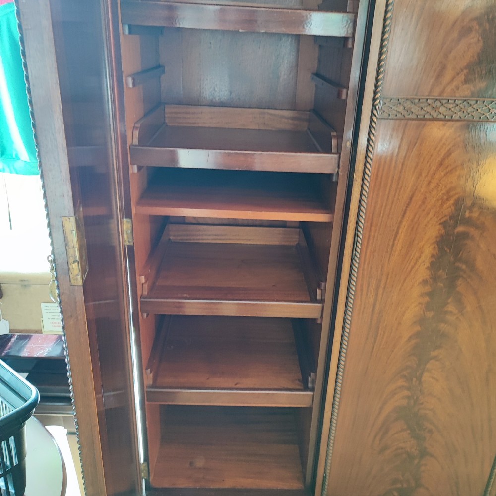An Edwardian flame mahogany three-door wardrobe featuring carved rope twist moulding and carved bracket feet. View VII