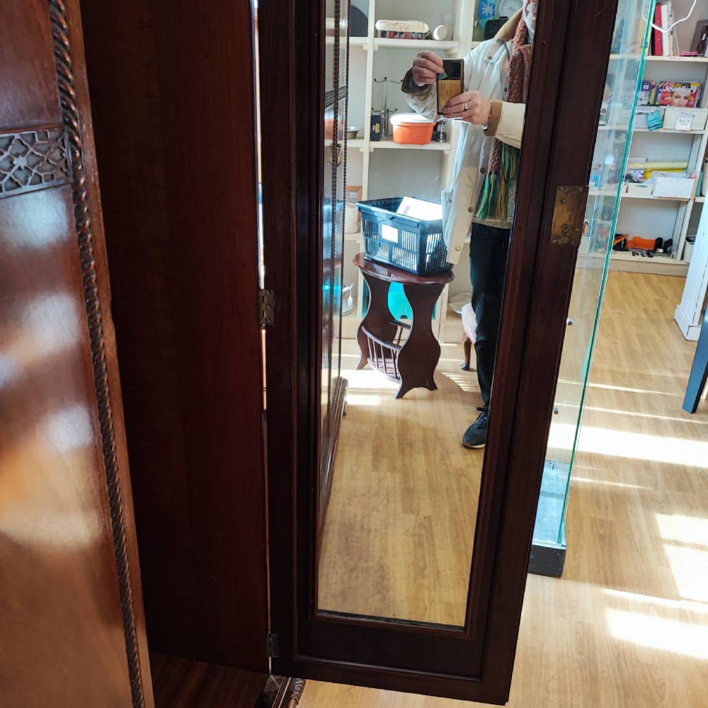 An Edwardian flame mahogany three-door wardrobe featuring carved rope twist moulding and carved bracket feet. View X