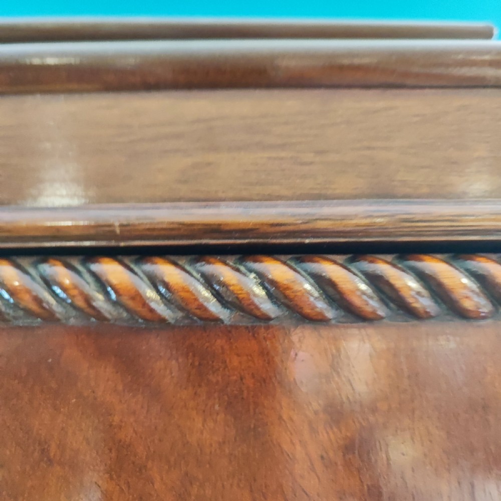 An Edwardian flame mahogany three-door wardrobe featuring carved rope twist moulding and carved bracket feet. View XIII