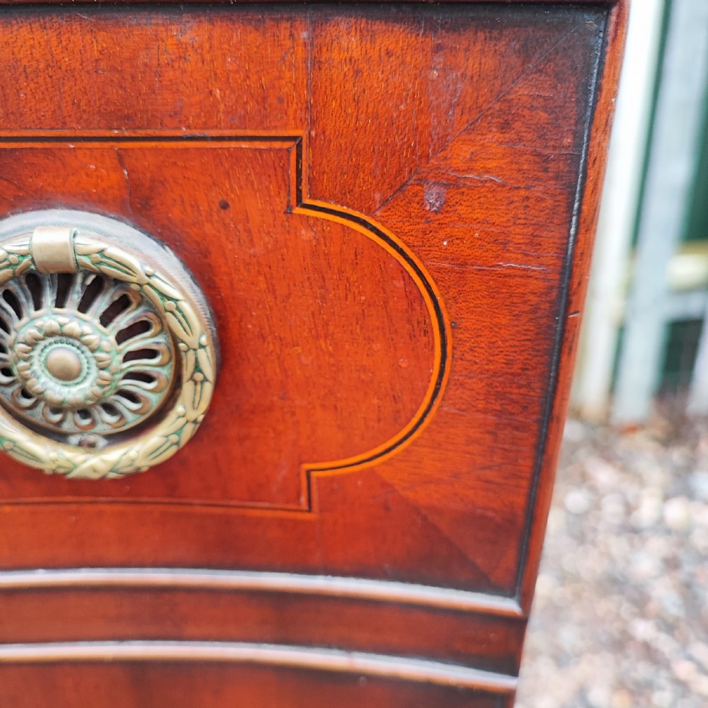 A George III style serpentine mahogany sideboard featuring marquetry inlay, brass ring handles, an arched central drawer, and square tapered legs. View VII