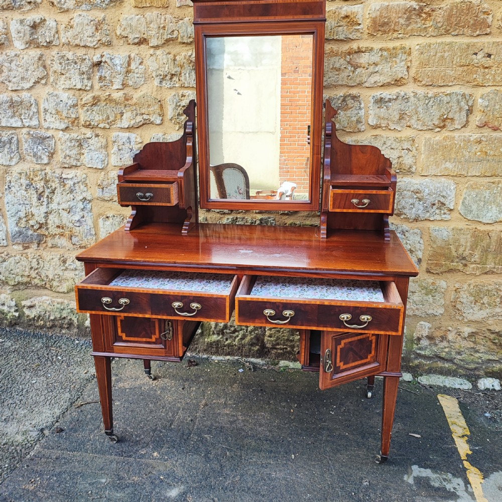 An Edwardian mahogany dressing table with satinwood inlay, an upright swinging central mirror, upper trinket drawers, and main drawers on tapering legs. View III