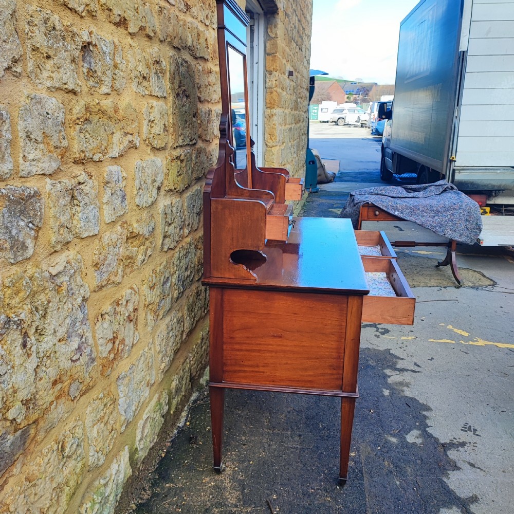 An Edwardian mahogany dressing table with satinwood inlay, an upright swinging central mirror, upper trinket drawers, and main drawers on tapering legs. View V