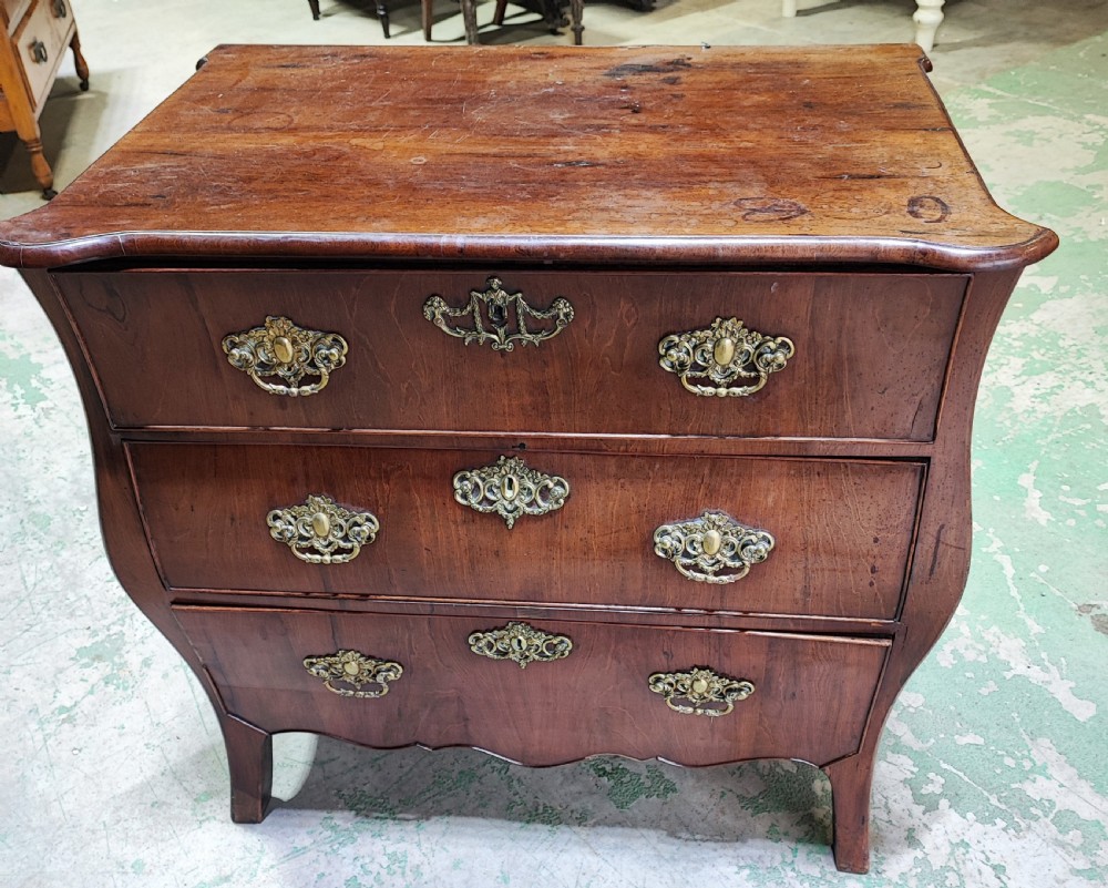 An eighteenth-century Dutch mahogany chest of drawers with a bombee front, three drawers, and cast brass handles. View VI