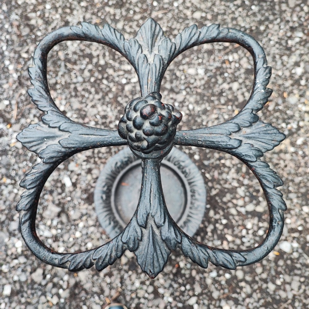 A Victorian black cast iron stick stand with an acorn finial, a four-section umbrella divider, and a circular leaf-embossed drip tray. View II