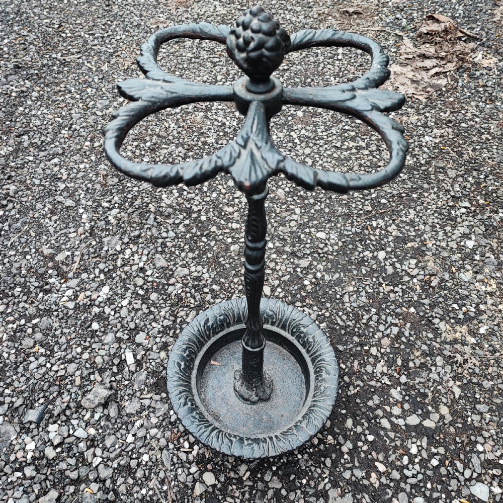 A Victorian black cast iron stick stand with an acorn finial, a four-section umbrella divider, and a circular leaf-embossed drip tray. View IV