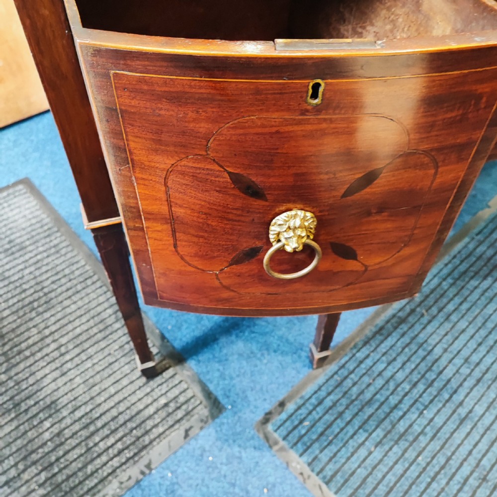 A Regency mahogany bowfront sideboard featuring inlaid floral motifs, brass lion-mask ring handles, and tapered square legs. View VI