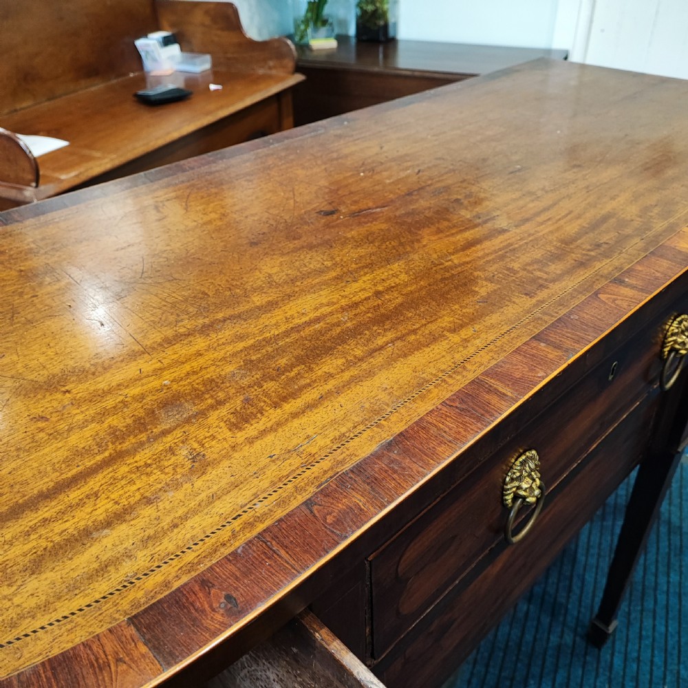 A Regency mahogany bowfront sideboard featuring inlaid floral motifs, brass lion-mask ring handles, and tapered square legs. View VIII
