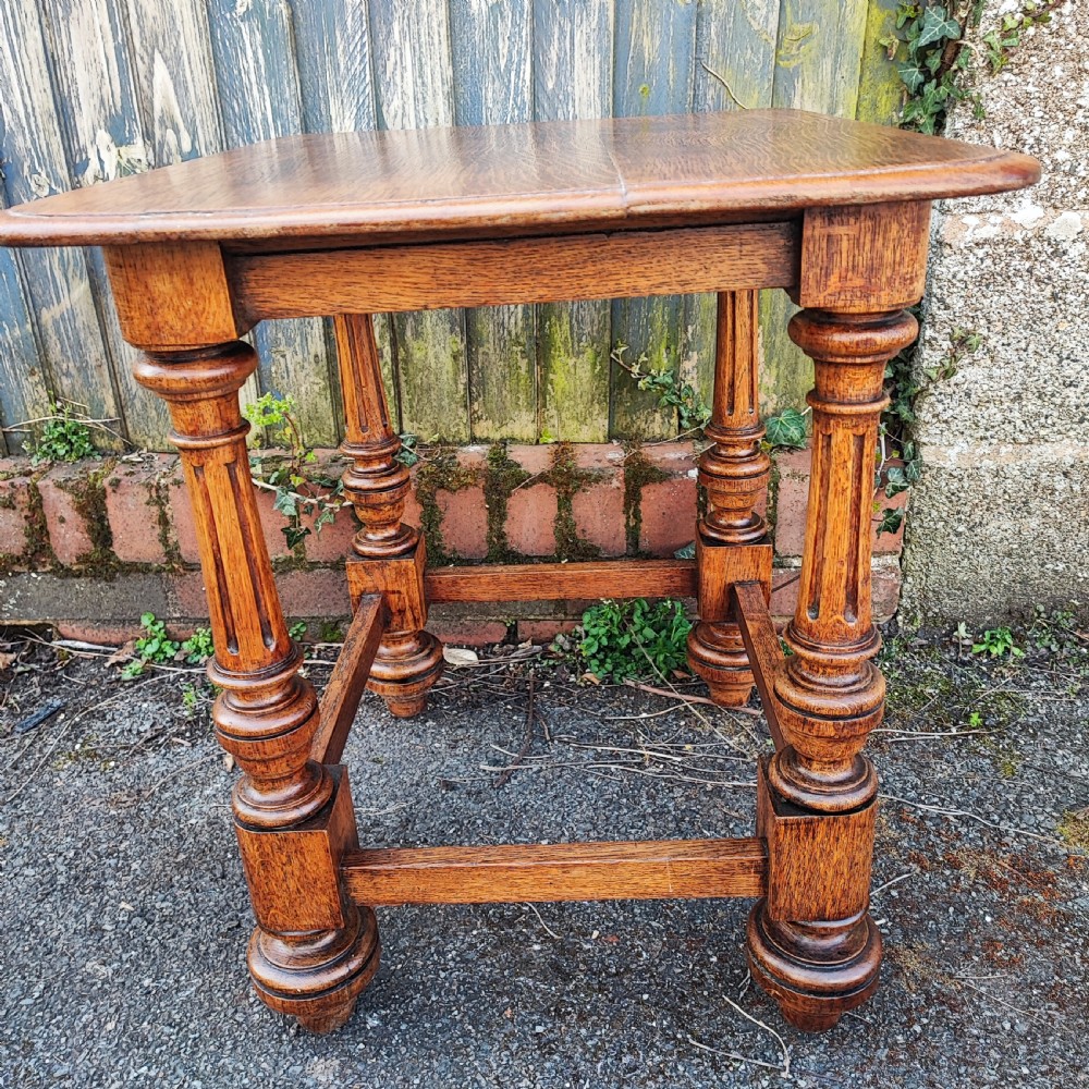 An antique oak low side table featuring fluted turned legs, square block joints, lower perimeter stretchers, and a rectangular top with moulded edges.